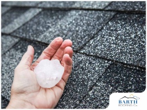Hand holding large hail on top of a roof